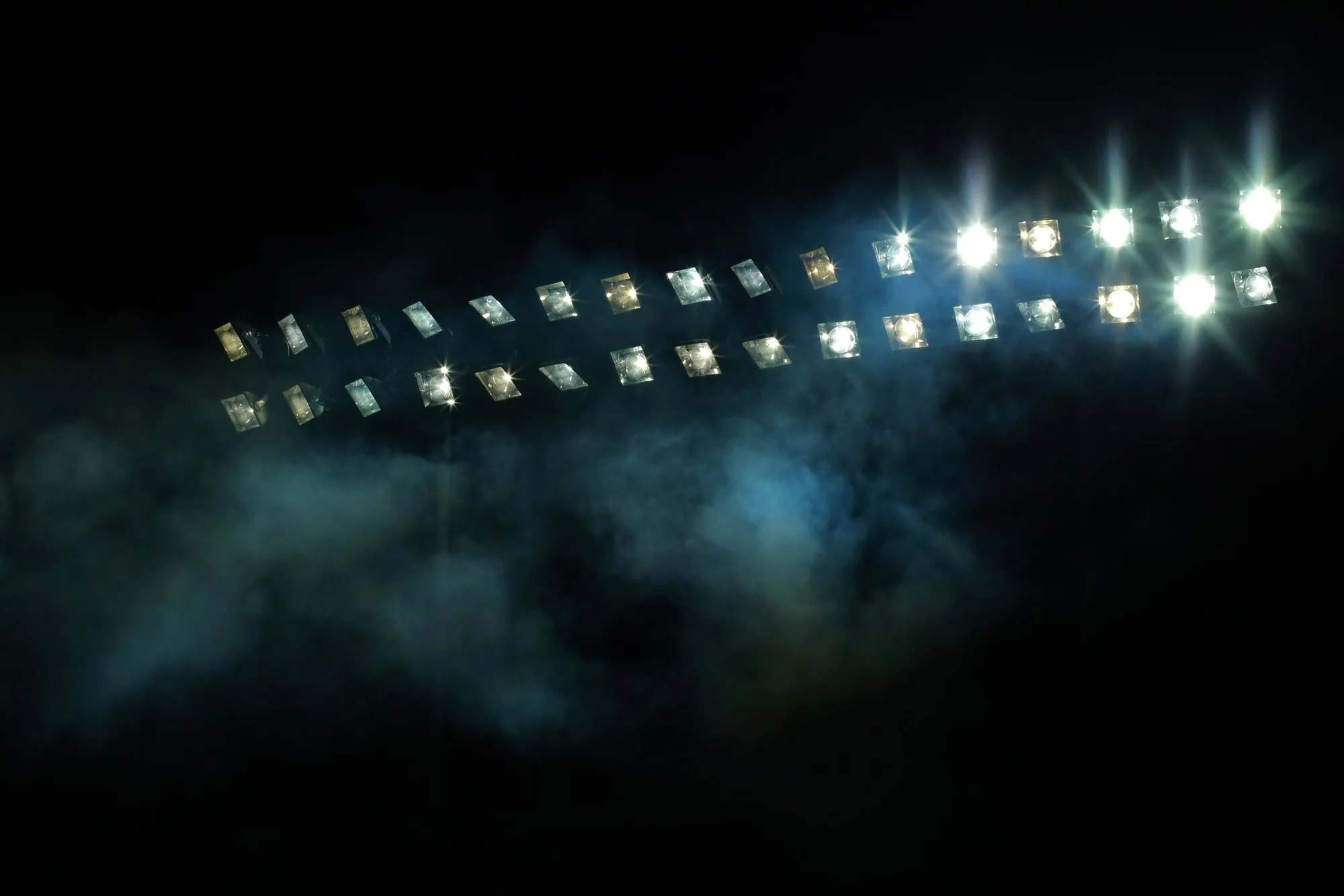 A bank of floodlights glowing through night mist